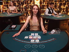 Ein weiblicher Dealer an einem Casino Poker Tisch im Live Casino.
