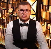 Abgebildet ist den Croupier Vitalijs bei einer Runde Caribbean Stud Poker.