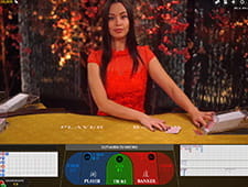 Zu sehen ist eine Live Dealerin, die an einem Spieltisch mit Online Spielern Baccarat spielt.