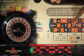 Zu sehen ist ein Roulettetisch von oben und Spieler, die ihre Jetons setzen.