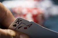 Eine Hand deckt beim Blackjack die beiden Spielkarten Pik König und Karo Ass auf.