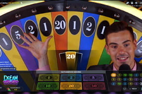 Zu sehen ist ein Moderator, der die Gewinnzahl des Glücksraddrehs anzeigt.