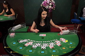 Auf dem Bild seht ihr eine schwarzhaarige Dealerin, die gerade verschiedene Blackjack Hände gibt.